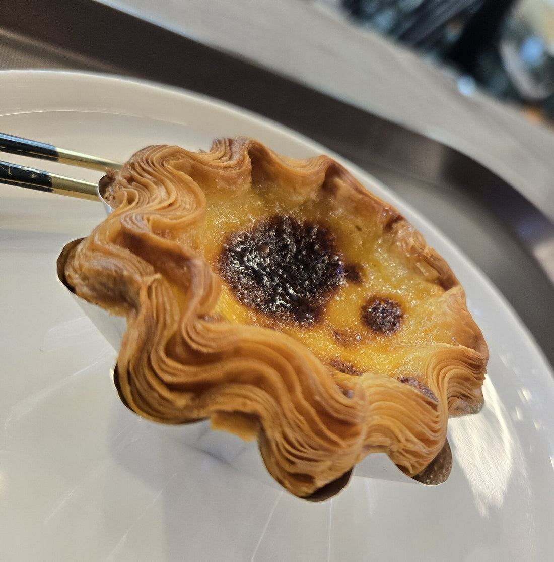 The flaky layered shell of a Barista Kang egg tart