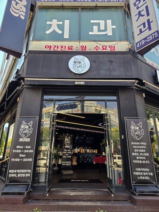The black corner storefront of BOSSS Coffee in Ansan with its German shepherd mascot sign